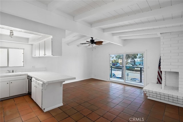 kitchen with a peninsula, tile counters, white cabinetry, tile patterned floors, and a sink