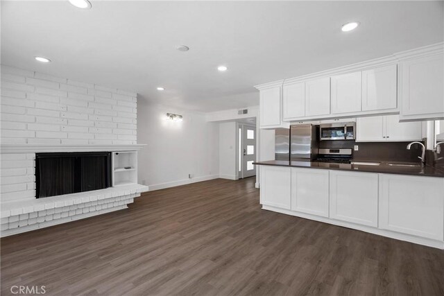 207 28th St, Newport Beach, CA 92663 - kitchen featuring stainless steel appliances, dark countertops, a sink, white cabinetry, and a brick fireplace