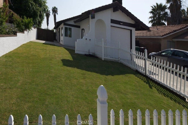 view of home's exterior with a garage, stucco siding, a lawn, a fenced front yard, and driveway