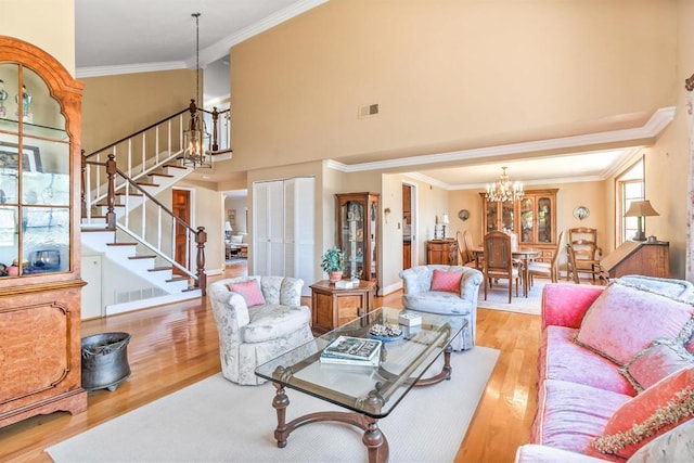 living area featuring a towering ceiling, wood finished floors, a notable chandelier, and stairway