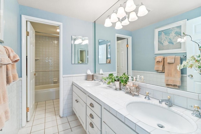 full bathroom featuring a sink, tile walls, tile patterned flooring, and double vanity