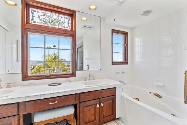 bathroom featuring visible vents, a sink, double vanity, and a relaxing tiled tub