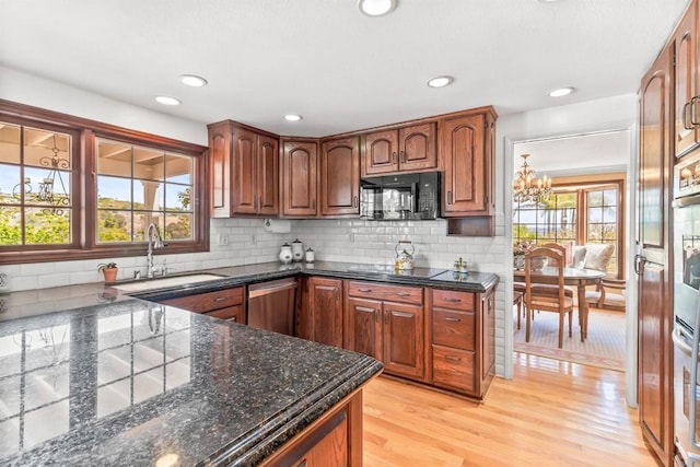 kitchen featuring light wood-type flooring, a sink, dark stone countertops, a notable chandelier, and stainless steel appliances
