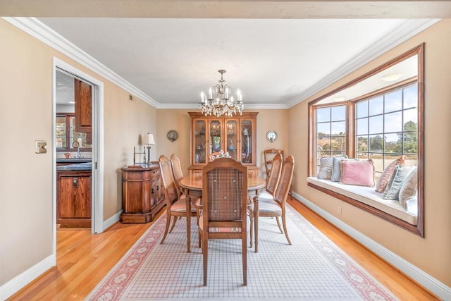 dining space featuring crown molding, light wood-style flooring, and a chandelier