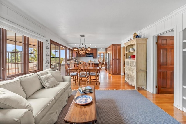 living room with recessed lighting, an inviting chandelier, ornamental molding, and light wood-style floors