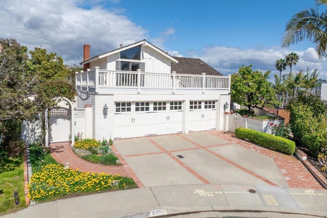 view of property with fence, a balcony, a gate, concrete driveway, and an attached garage