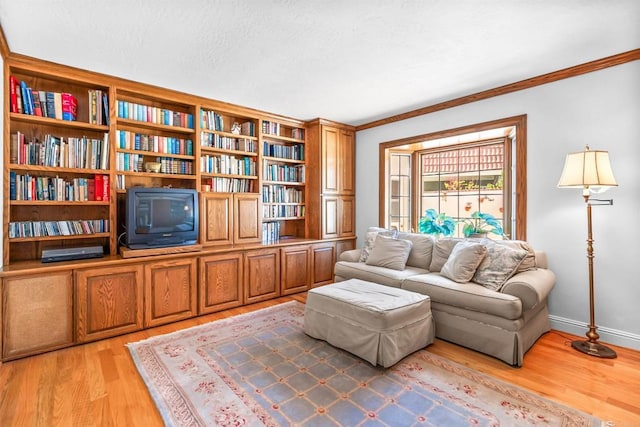 sitting room with light wood-style floors, baseboards, ornamental molding, and a textured ceiling