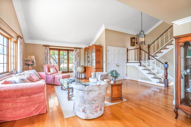 living area featuring a notable chandelier, ornamental molding, wood finished floors, and stairway