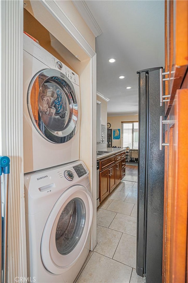 washroom with stacked washer / drying machine, recessed lighting, light tile patterned flooring, and laundry area