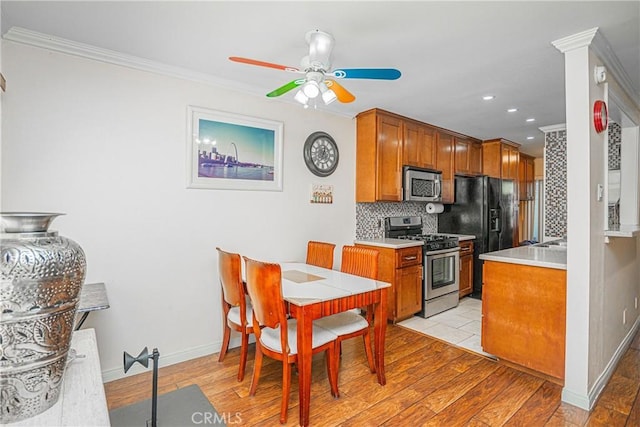 kitchen featuring stainless steel appliances, ceiling fan, decorative backsplash, and light wood-style floors
