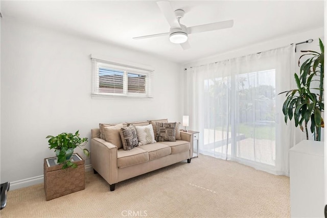 living room featuring a ceiling fan, light colored carpet, and a wealth of natural light
