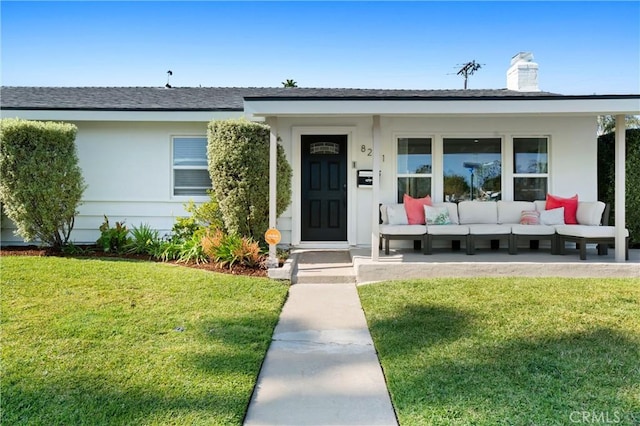 entrance to property with a lawn, outdoor lounge area, a chimney, and stucco siding