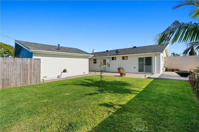 rear view of house with a lawn, stucco siding, and a patio area