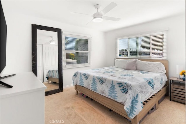 bedroom with a ceiling fan, light carpet, and multiple windows