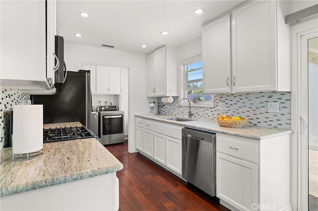 kitchen featuring a sink, appliances with stainless steel finishes, backsplash, and dark wood-style flooring