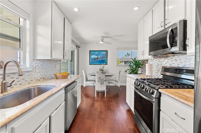 kitchen featuring ceiling fan, appliances with stainless steel finishes, a sink, baseboards, and tasteful backsplash