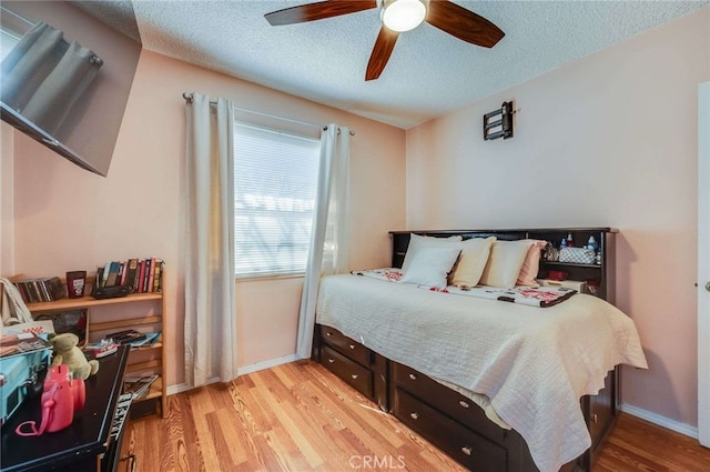 bedroom with light wood-style floors, baseboards, a ceiling fan, and a textured ceiling