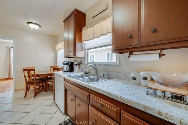 kitchen featuring light countertops, white dishwasher, light tile patterned floors, and a sink