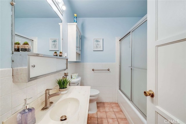 full bathroom featuring tile patterned flooring, vanity, toilet, tile walls, and combined bath / shower with glass door