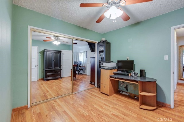 office space with light wood-style floors, baseboards, ceiling fan, and a textured ceiling