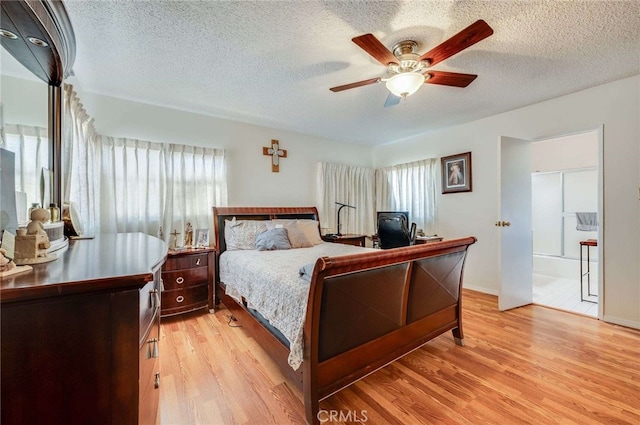 bedroom featuring multiple windows, light wood-type flooring, and a textured ceiling
