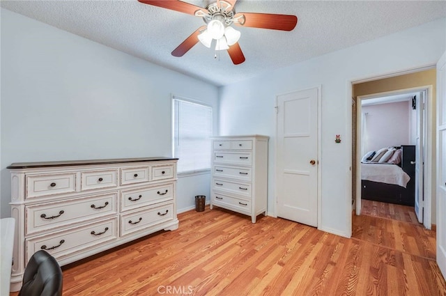 bedroom with a textured ceiling, ceiling fan, and light wood finished floors