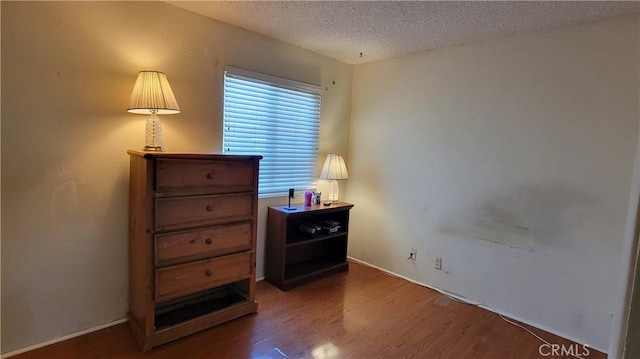 bedroom with baseboards, a textured ceiling, and wood finished floors