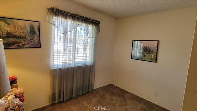 spare room with dark colored carpet