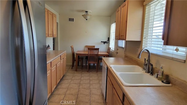kitchen with visible vents, freestanding refrigerator, light countertops, a sink, and light tile patterned floors