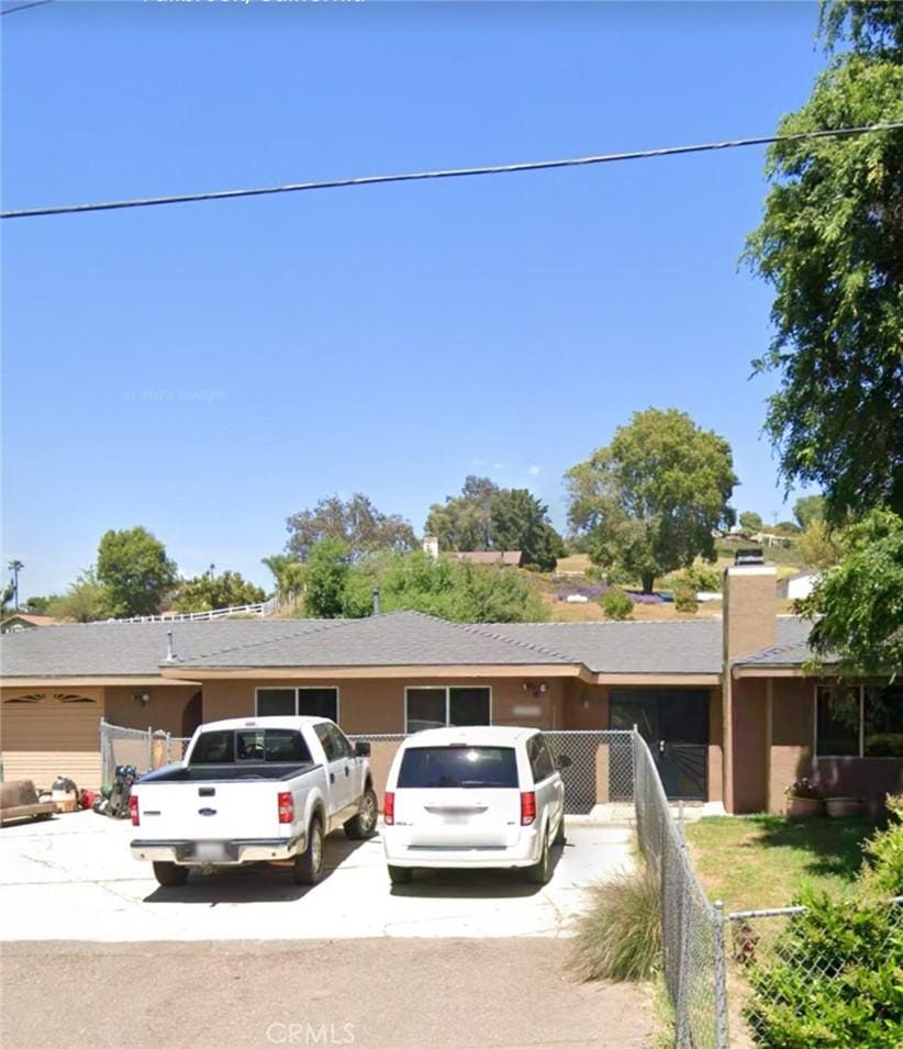 single story home featuring concrete driveway and fence