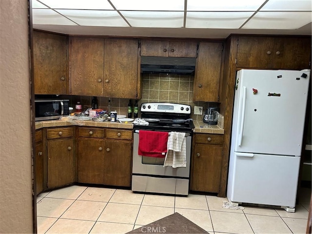 4644 La Canada Rd, Fallbrook, CA 92028 - kitchen featuring stainless steel appliances, under cabinet range hood, light tile patterned floors, backsplash, and dark brown cabinetry