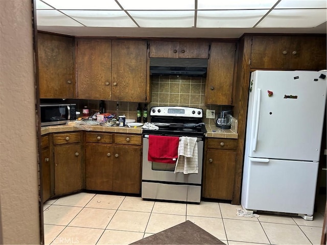 4644 La Canada Rd, Fallbrook, CA 92028 - kitchen with appliances with stainless steel finishes, under cabinet range hood, light tile patterned floors, and tile countertops