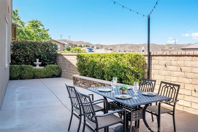 view of patio with a fenced backyard, a mountain view, and outdoor dining space