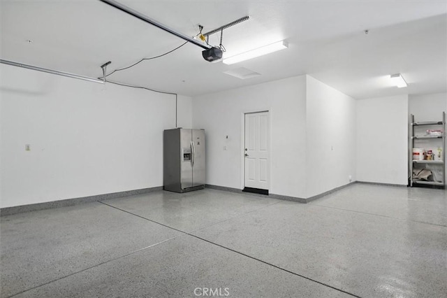 garage featuring stainless steel refrigerator with ice dispenser, baseboards, and a garage door opener