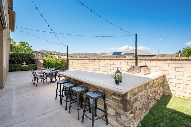 view of patio featuring an outdoor kitchen, a fenced backyard, and outdoor dry bar