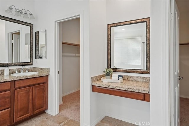 bathroom with vanity, baseboards, and a spacious closet