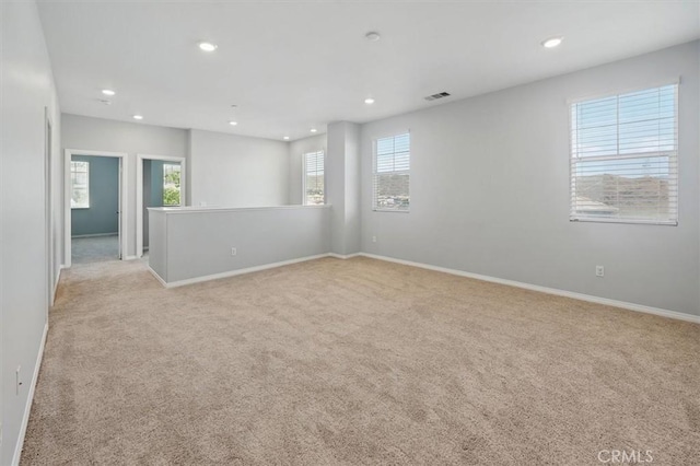 spare room with recessed lighting, light carpet, and a wealth of natural light
