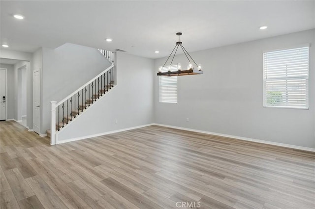 empty room with recessed lighting, light wood-style flooring, stairs, and a wealth of natural light