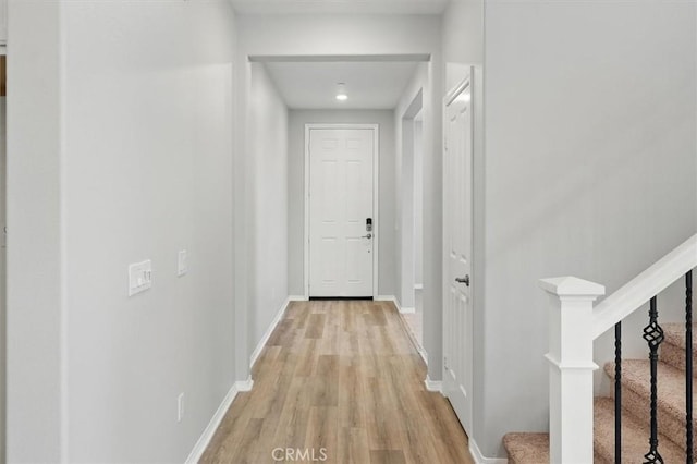 corridor featuring stairs, recessed lighting, baseboards, and light wood-type flooring