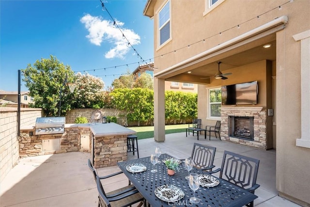 view of patio / terrace with fence private yard, an outdoor stone fireplace, a bar, an outdoor kitchen, and a grill