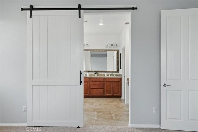 interior space with a sink, baseboards, and a barn door