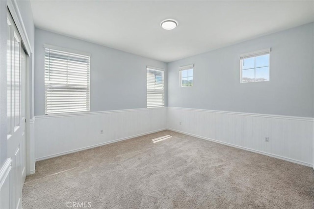 carpeted empty room with wainscoting