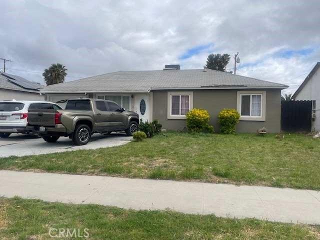 single story home with an attached garage, stucco siding, concrete driveway, and a front lawn