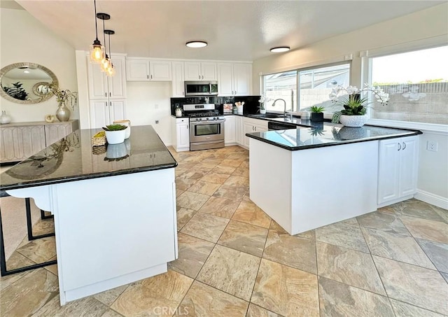 kitchen with hanging light fixtures, stainless steel appliances, white cabinetry, a peninsula, and decorative backsplash