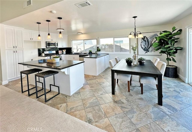 kitchen featuring a sink, dark countertops, stainless steel appliances, and visible vents