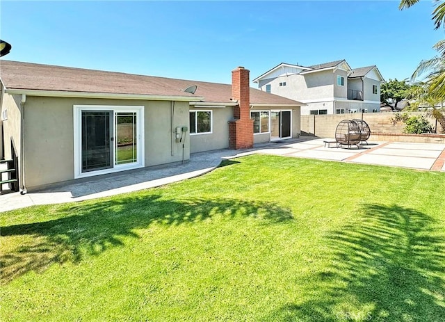 back of property featuring a patio, a fenced backyard, stucco siding, a chimney, and a yard
