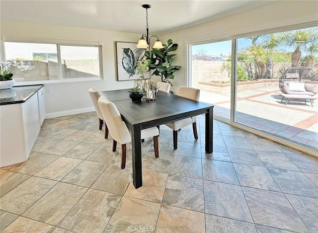 dining space with baseboards, a notable chandelier, and a wealth of natural light
