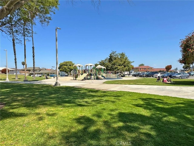 surrounding community with a lawn, uncovered parking, and playground community