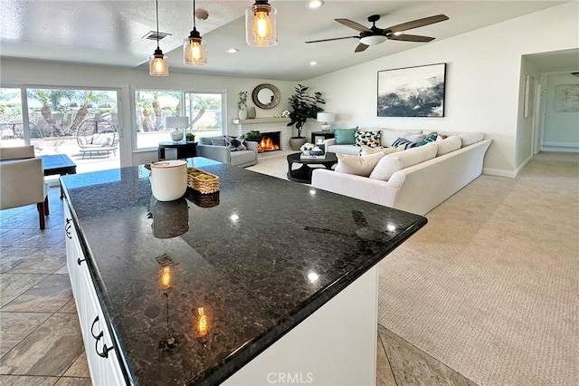 kitchen with visible vents, a kitchen island, a fireplace, open floor plan, and white cabinetry