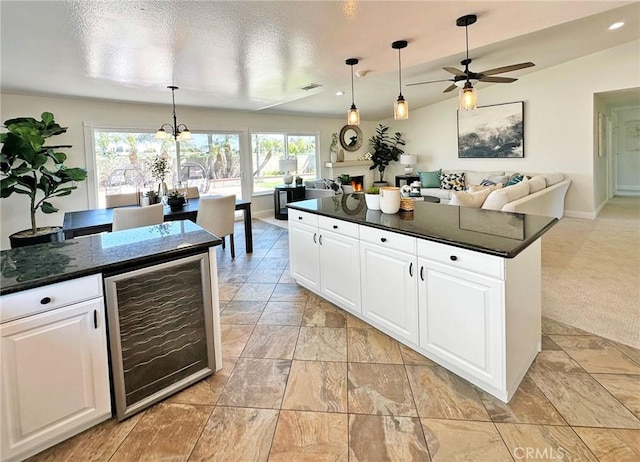 kitchen with white cabinetry, dark countertops, ceiling fan with notable chandelier, and wine cooler